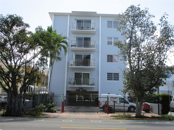 Front view of a multi-story residential building with balconies and gated parking.