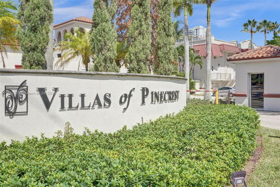 Front elevation of a building with a sign reading 'Villas of Pinecrest' and Mediterranean architecture.