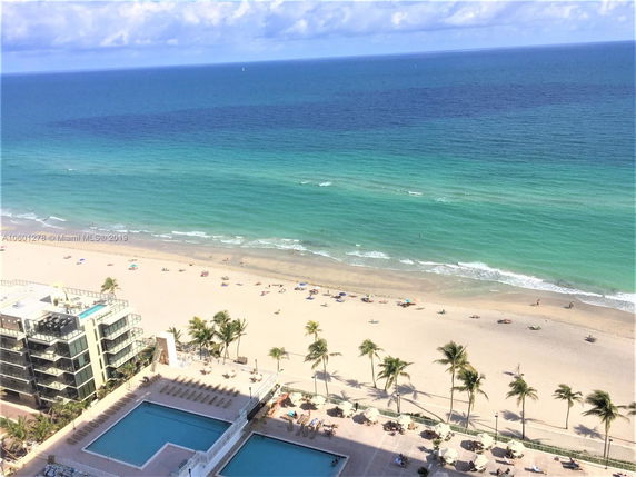 Aerial view of a beachfront with a swimming pool and adjacent ocean.