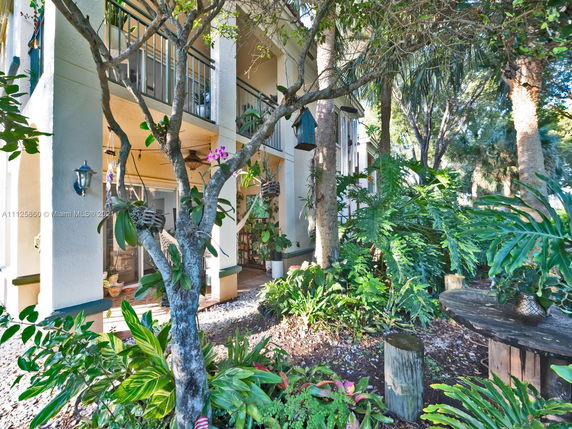 Front view of a house with a lush garden and balcony.