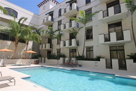 Front view of a multi-story building with balconies and a pool area.