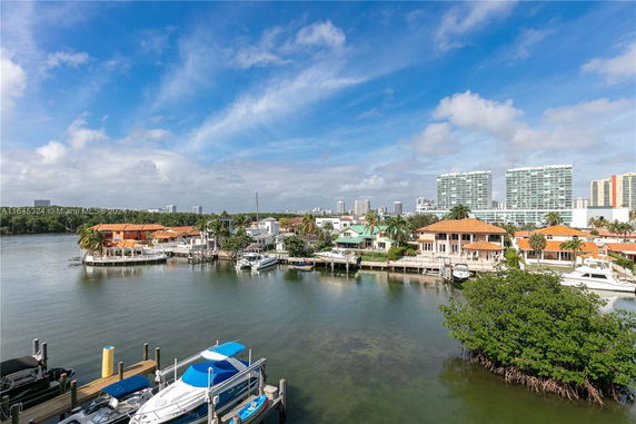 Aerial view of waterfront residential area with houses, docks, and boats along a waterway.
