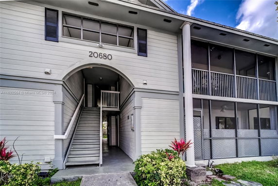 Front view of a two-story building with an archway entrance and screened balconies.