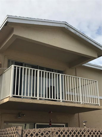 Front view of a two-story house with a small balcony and a sloped roof.
