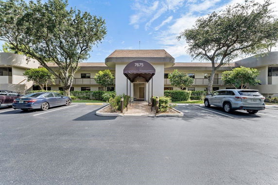 Front view of a two-story building with a central entrance and outdoor parking.