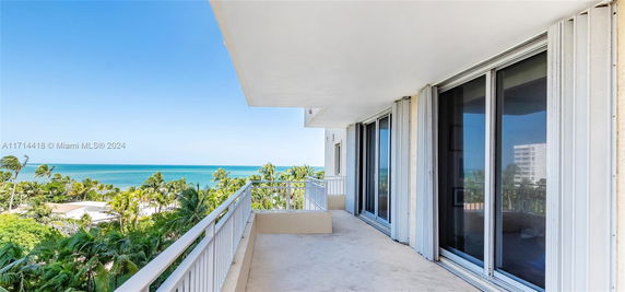 Balcony view overlooking ocean and palm trees.