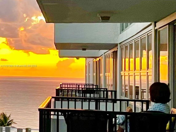 View of a building's balconies with a sunset over the ocean in the background.