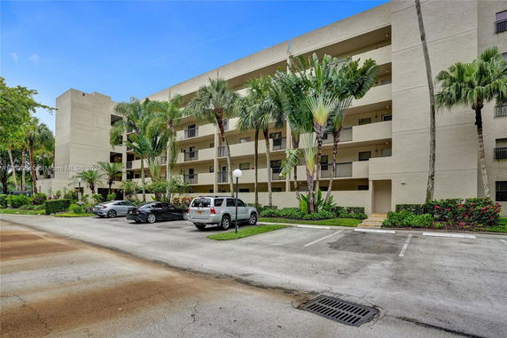 Front view of a multi-story apartment building with a parking area in front.