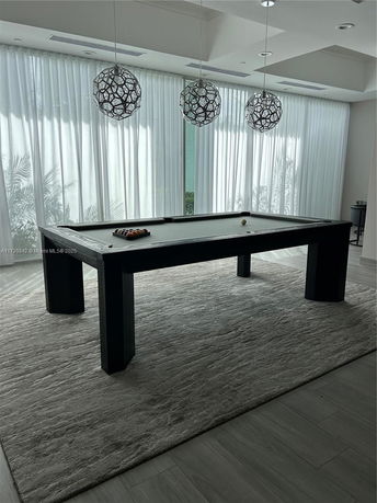 Room with a billiards table and modern pendant lights.