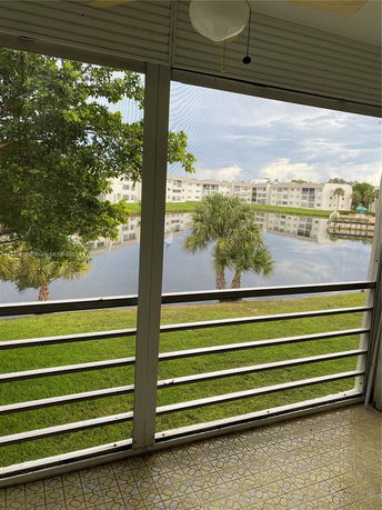 View from a balcony showing a pond and residential buildings in the background.