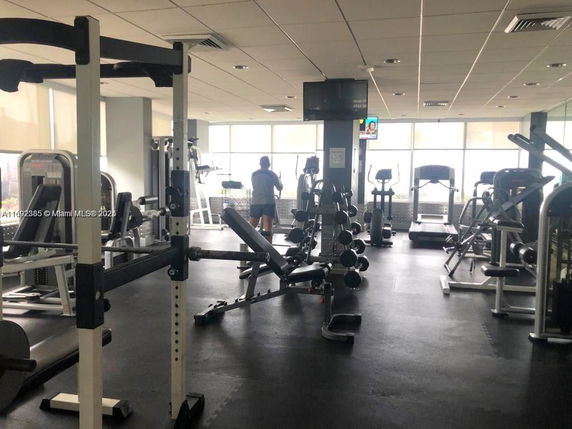 Interior view of a gym area with various exercise equipment and a person working out.