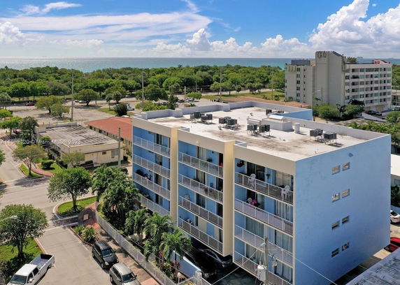 Front view of a multi-story apartment building with balconies and rooftop air conditioning units.