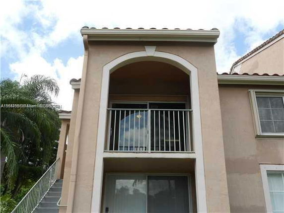 Front view of a two-story building with balconies and stucco exterior.