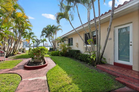 Front view of a single-story house with a walkway and tropical landscaping.