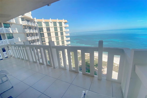 View from a balcony overlooking a building and the ocean.