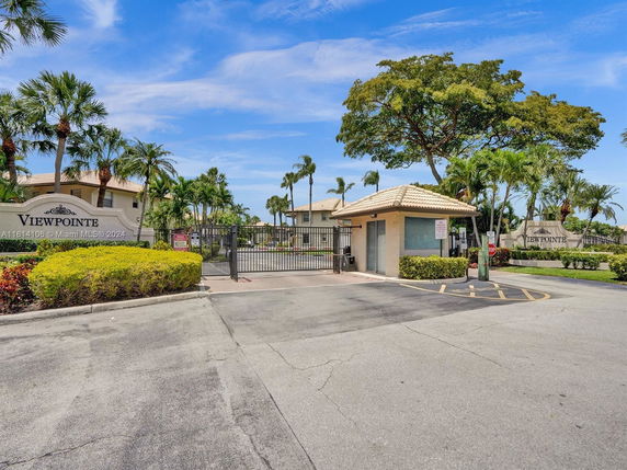 Front view of a gated community entrance with a small guardhouse.