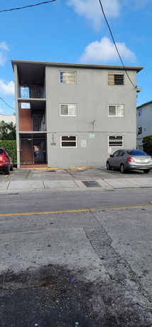Front view of a three-story apartment building with parking spaces in front.