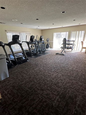 Room with exercise equipment including treadmills and weights.