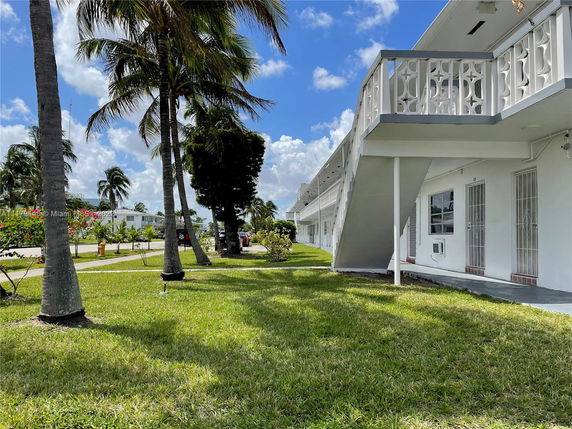 Side view of a two-story residential building with palm trees in the foreground.