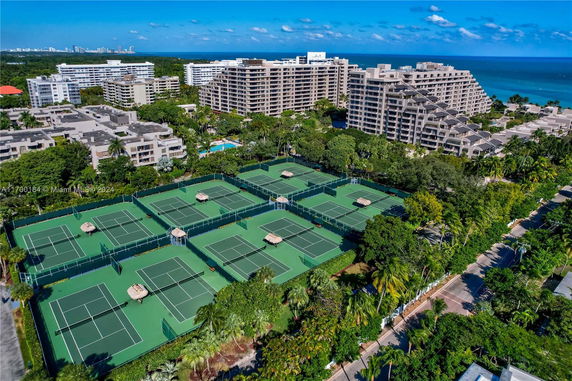 View of multiple tennis courts surrounded by residential buildings near the ocean.