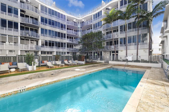 Outdoor view of a multi-story building with a swimming pool and lounge chairs.