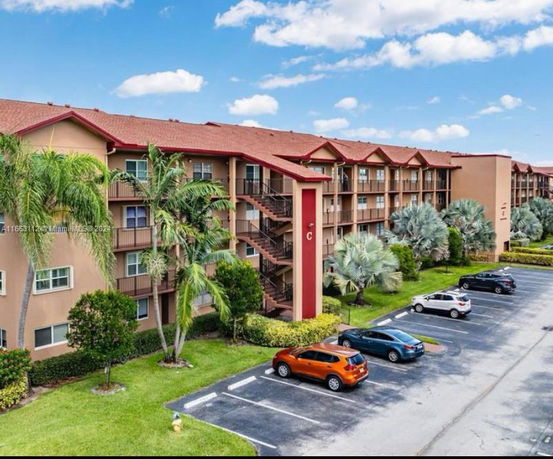 Front view of a multi-story apartment building with balconies and an exterior staircase.