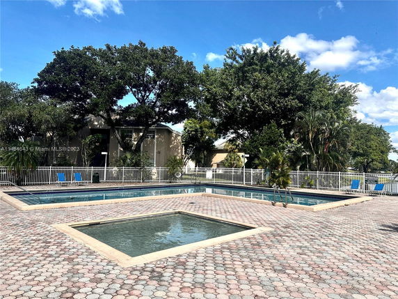 Outdoor swimming pool area with surrounding trees and lounge chairs.