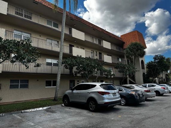 Front view of a multi-story residential building with balconies and parking area.
