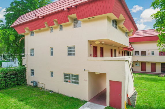 Front view of a beige multi-story building with red roof and multiple windows.