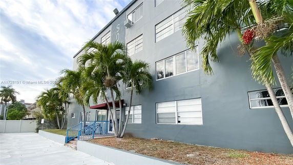 Front view of a multi-story building with tall windows and palm trees.