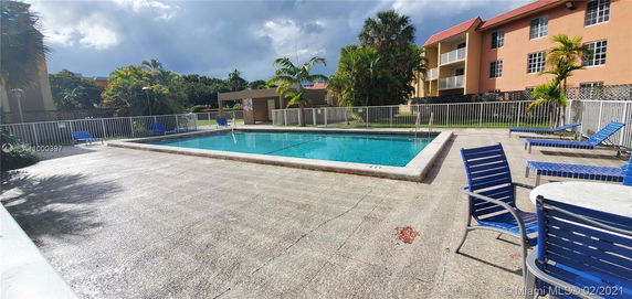 Outdoor swimming pool area with lounge chairs and a fenced perimeter.