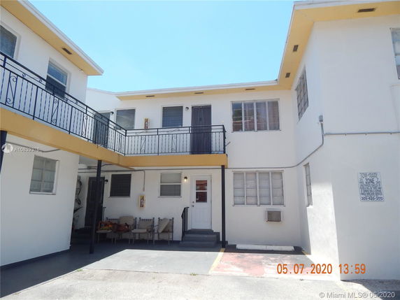 Front view of a two-story building with balconies and outdoor seating area.