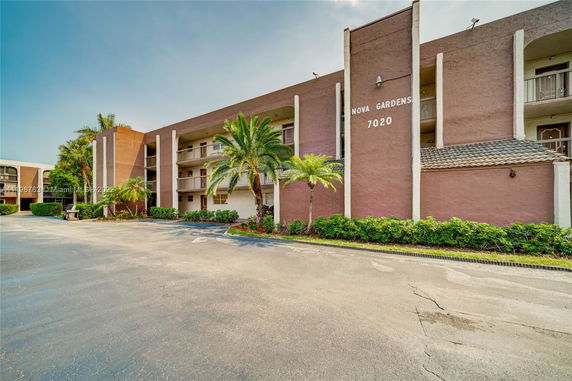 Front view of a multi-story residential building with balconies and brown exterior walls.