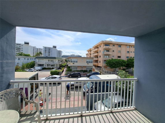 View from a balcony showing buildings and parked vehicles in an urban area.