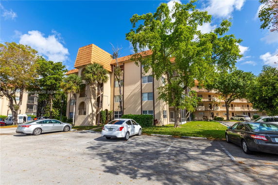 Outdoor parking area in front of a multi-story residential building with balconies.