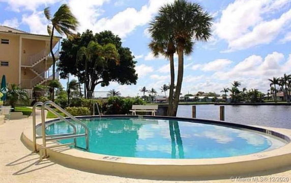 Swimming pool view with a waterway and palm trees in the background.