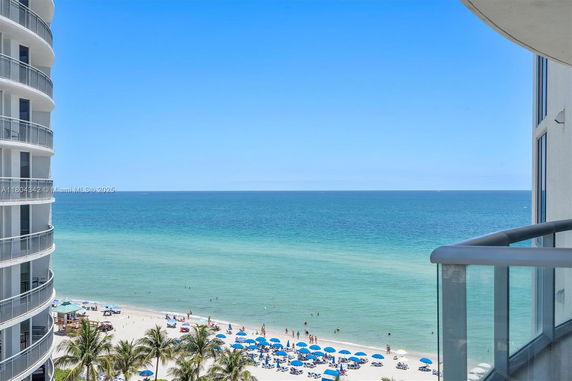 Coastal view from a balcony with visible beach and ocean.