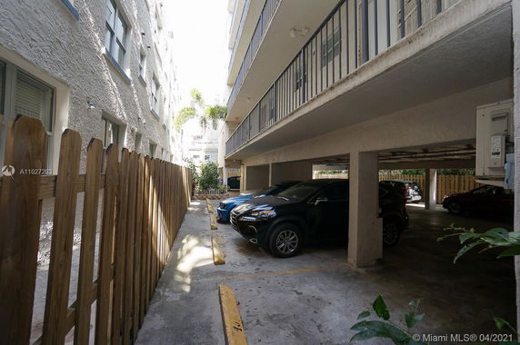 Outdoor covered parking area adjacent to a multi-story building.
