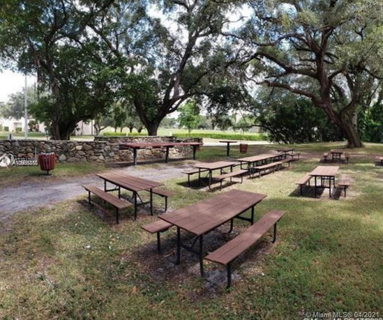 Outdoor area with picnic tables and large trees.