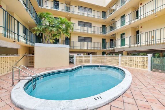 Outdoor view of a multi-story residential building with a small swimming pool in the courtyard.