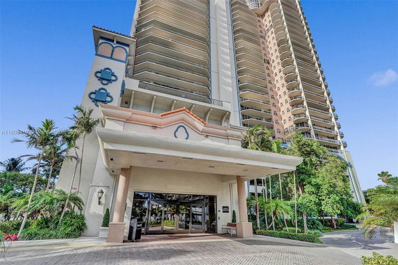 Front view of a tall residential building with multiple balconies.