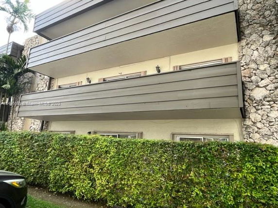Front view of a multi-story building with distinctive stone walls and horizontal cladding.