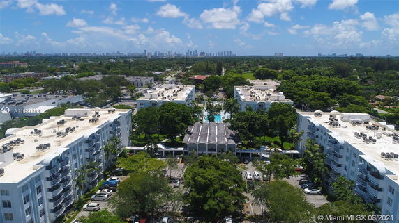 Aerial view of apartment buildings with white rooftops and outdoor air conditioning units.