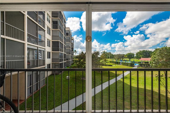 View from a balcony looking out at surrounding greenery and residential buildings.