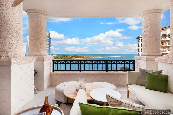 View of surrounding areas featuring ocean and distant buildings from a balcony with decorative columns.