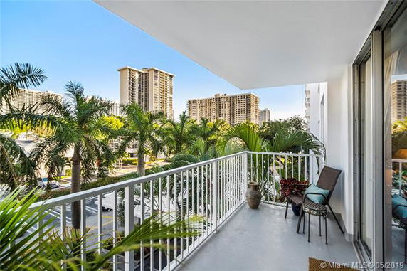View from a balcony overlooking buildings and palm trees.