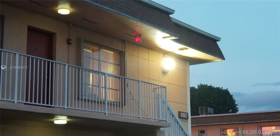 View of a building exterior with a balcony and exterior lighting.