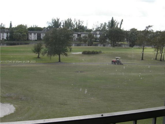 View of a grassy area with trees and buildings in the background.
