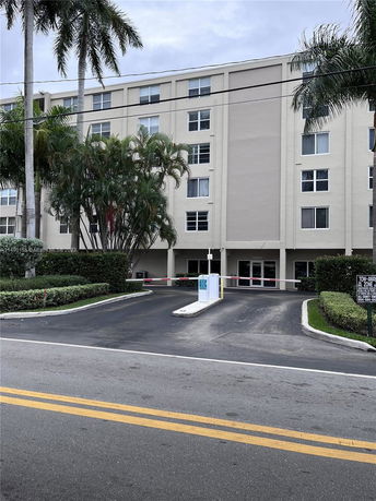 Front view of a multi-story residential building with an entrance driveway.