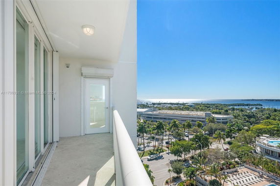 Balcony view overlooking a coastal area with trees and buildings.